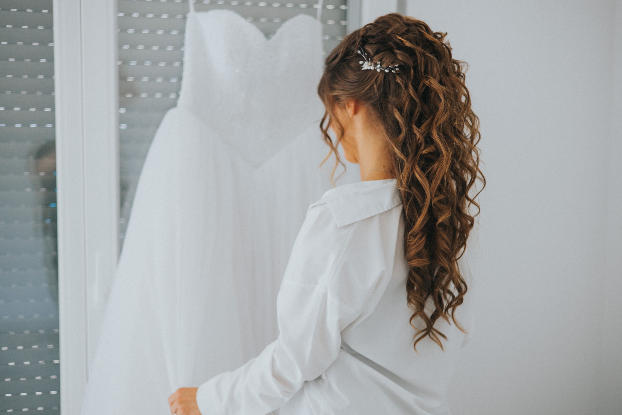 Bride with beautiful hair observing her bridal dress on her wedding day