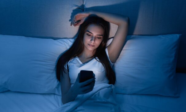 Woman browsing smartphone in bed at night