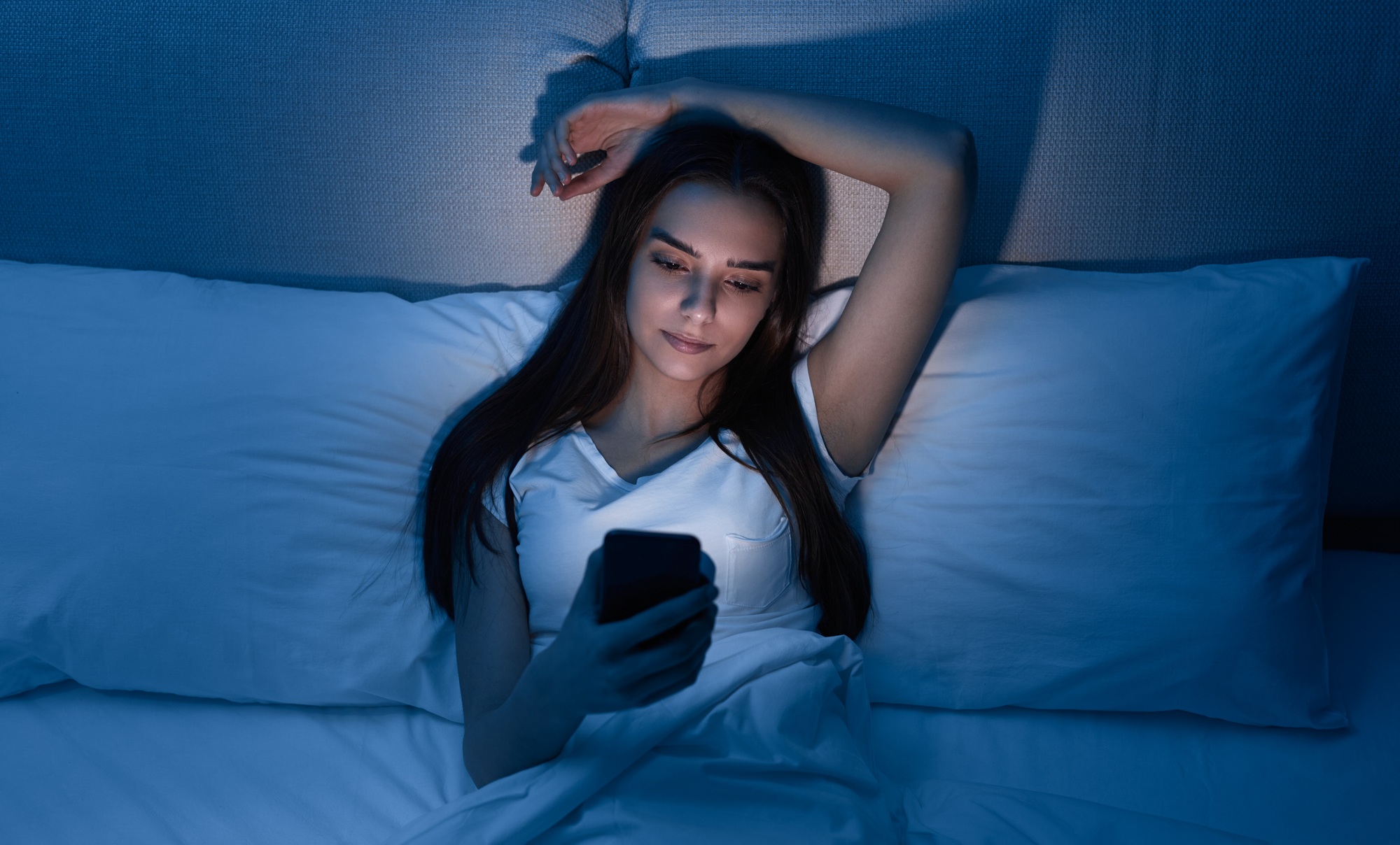 Woman browsing smartphone in bed at night