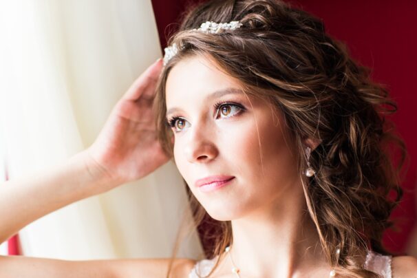 Beautiful young bride with wedding makeup and hairstyle in bedroom