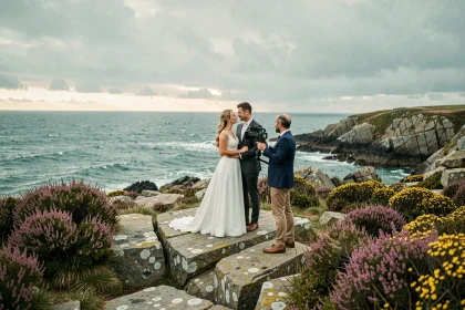 Vidéaste filmant un couple de mariés sur la côte bretonne avec l'océan Atlantique en arrière-plan